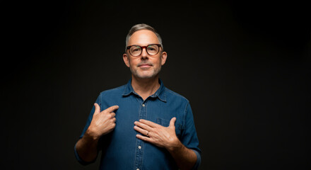 Fototapeta premium Confident adult caucasian male with glasses in denim shirt on black background