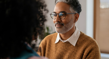 Fototapeta premium Mature hispanic male with glasses engaging in conversation indoors