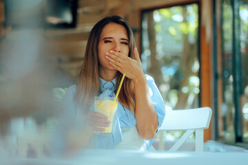 Woman Drinks Lemonade and Covers Her Mouth in a Restaurant. Lady belching feeling uncomfortable...