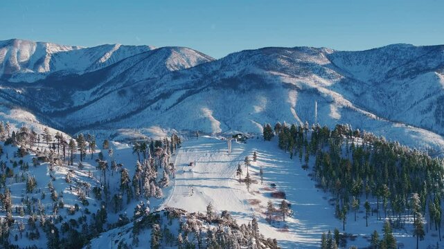 Experience a drones breathtaking view of a snow groomer smoothing fresh powder on Big Bears picturesque hills under a mesmerizing sunset, creating a truly unforgettable winter getaway