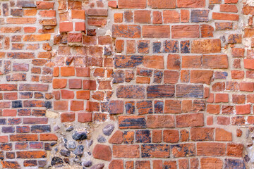 Fragment of an old brick and fieldstone wall. Close-up of a historic wall made of red brick and...