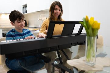 Mother teaching son playing piano at home during music lesson