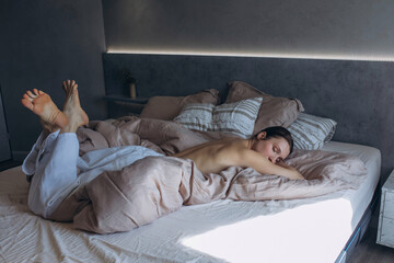 A beautiful brunette woman in the bedroom on the bed in white jeans