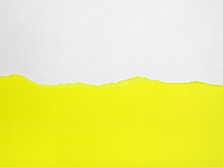 A vibrant yellow piece of paper is torn, revealing a white background underneath