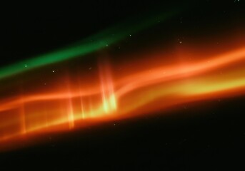 Fototapeta premium Aurora borealis displaying vibrant colors of green and orange against the dark night sky above