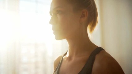 Focused woman in sportswear preparing for morning workout routine in sunlit room, capturing strength, discipline, and wellness, ideal for fitness, health, and lifestyle content

