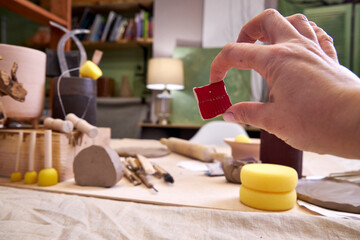 Close-up of a ceramic tile sample in hand against the background of a pottery workshop