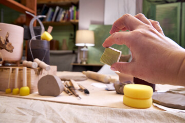 Close-up of a ceramic tile sample in hand against the background of a pottery workshop