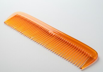 An orange plastic comb with fine teeth sitting diagonally on a plain white background studio shot