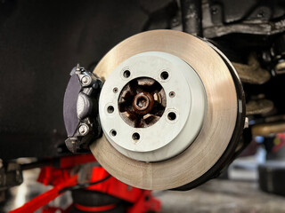 Car brake disc with red caliper. Modern brake disc with holes and cooling. Brake disc and wheel hub...