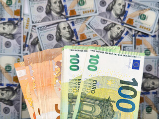 50 euro and 100 euro banknotes are higher than the dollar against a background of new US dollars with a denomination of 100 dollars, top view