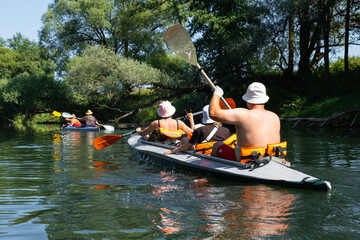 Family with children on rafting trip in Group kayak trip of different ages, adults, elderly. Rowing boat on the river, a water hike, summer adventure. 