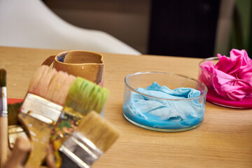 on a table in the workshop are glass flasks with dyed multicolored fabrics, side view