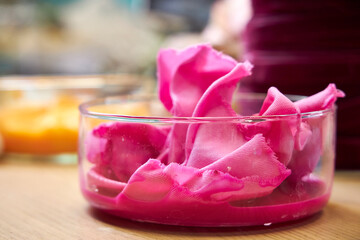 side view of glass flasks with dyed bright fuchsia-colored fabrics, closeup