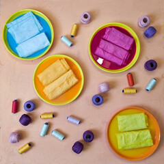 bright background for needlework, dyed colorful fabrics and skeins of thread lying on the table
