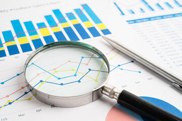 Magnifying glass on spreadsheet and graph paper. Financial data economy, Business.