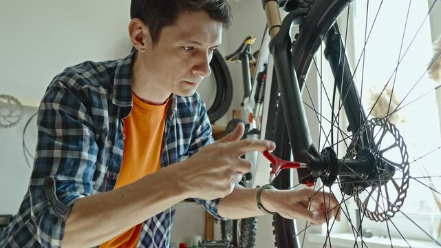 A male bicycle mechanic repairs a mountain bike in a repair shop. The concept of preparation for the new season, repair and maintenance