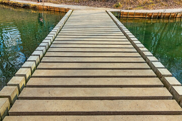 Concrete low footbridge on a stream or small river. Construction of a modern pedestrian bridge made of rectangular concrete blocks