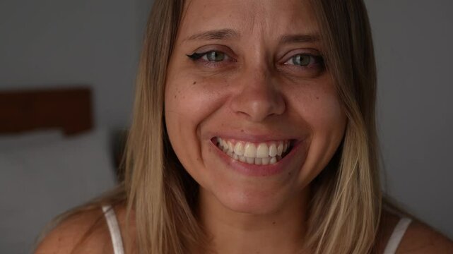Close-up of a young blonde woman crying and smiling at the same time feeling tears of joy. A deeply emotional and touching moment of happiness, release, and raw, heartfelt joy, truth