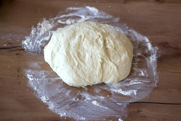 Ball of raw dough on a floured wooden surface