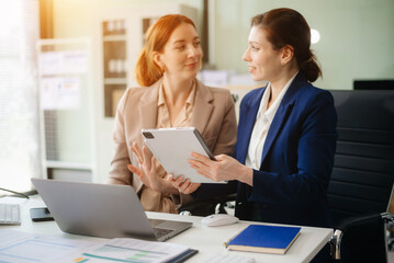 Businesswoman leading team meeting and using tablet and laptop computer with financial