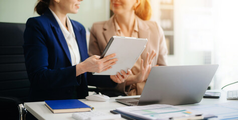 Two business workers talking on the smartphone and using laptop at the office..