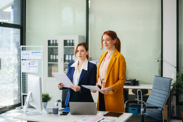 Businesswoman leading team meeting and using tablet and laptop computer with financial