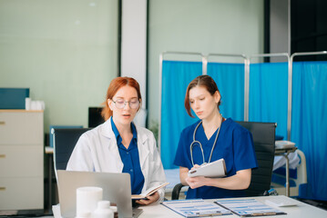 Doctor and nurse team using tablet to review medical results. Diverse healthcare professionals in modern hospital clinic