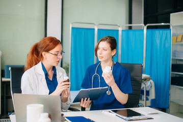 Doctor and nurse team using tablet to review medical results. Diverse healthcare professionals in modern hospital clinic