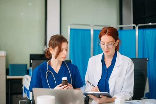 Doctor and nurse team using tablet to review medical results. Diverse healthcare professionals in modern hospital clinic