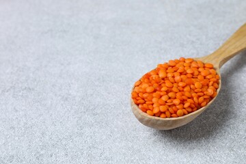 Red lentils in a spoon on a gray background