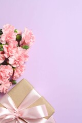 Happy Mother's Day. Beautiful bouquet of pink carnations with gift box on a colored background