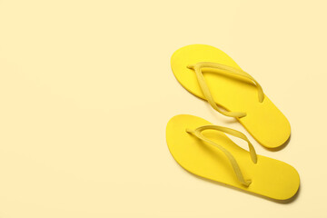Yellow flip-flops on beige background, top view