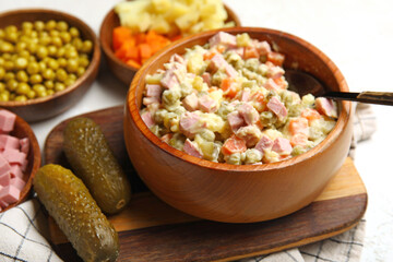 Bowl of tasty Olivier salad on light background, closeup