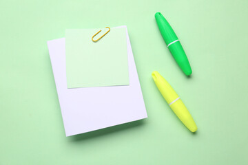 Sticky notes with paper clip and markers on green background