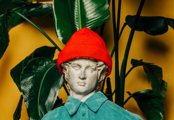 Antique statue  in a red hipster hat with a palm background
