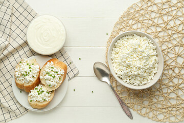 Baguette pieces with cottage cheese and sour cream on white wooden table