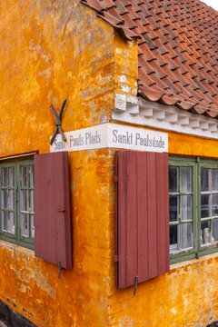 Historic corner detail from Nyboder, Copenhagen, with bold textures, warm ochre tones and wooden shutters in architectural harmony.