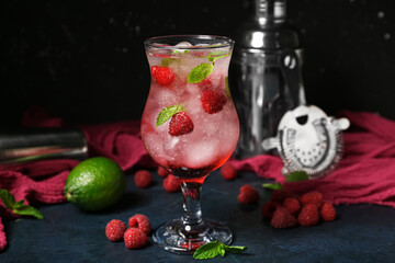 Glass of fresh raspberry mojito and shaker on blue table