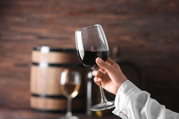 Female hand with glass of exquisite red wine on color background