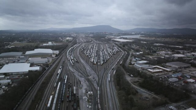 Aerial drone timelapse of the giant trainyard in Chattanooga, TN on a cloudy day with Lookout Mountain the background and many trains moving.