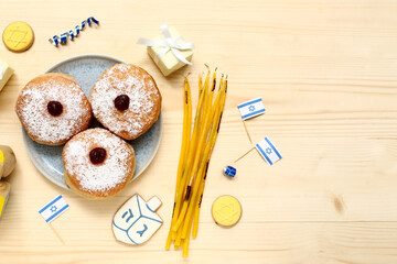 Composition with tasty donuts, candles and decor for Hanukkah celebration on wooden background