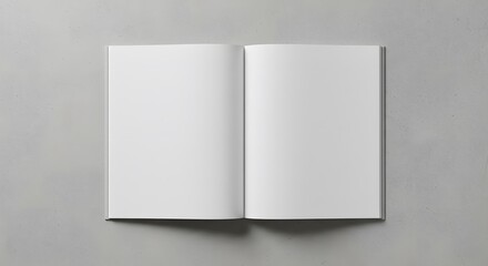 Fototapeta premium A clean, minimalist shot of an open, blank book laid flat on a concrete-like surface with ample white space.