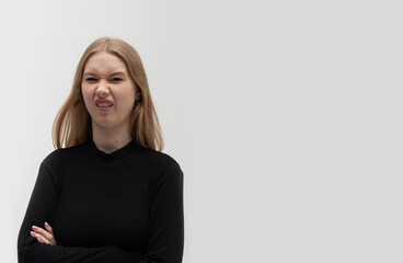 A young blonde girl wearing casual dark clothes has a disgusted expression, displeased and fearful,...
