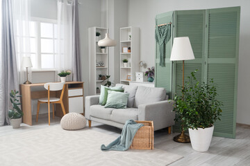 Interior of living room with green folding screen, sofa and plants