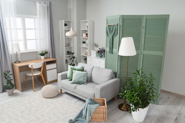 Interior of living room with green folding screen, sofa and plants