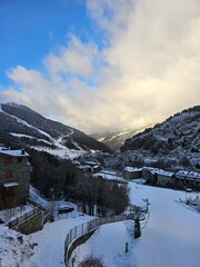 Snowy ski slopes and mountain village under blue sky in Andorra.