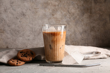 Glass of iced latte and sweet cookies on grey background