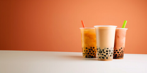 Colored bubble tea drinks in plastic cups with tapioca balls on orange background. Refreshing drinks for summer menu, advertising or promotion of Asian drinks