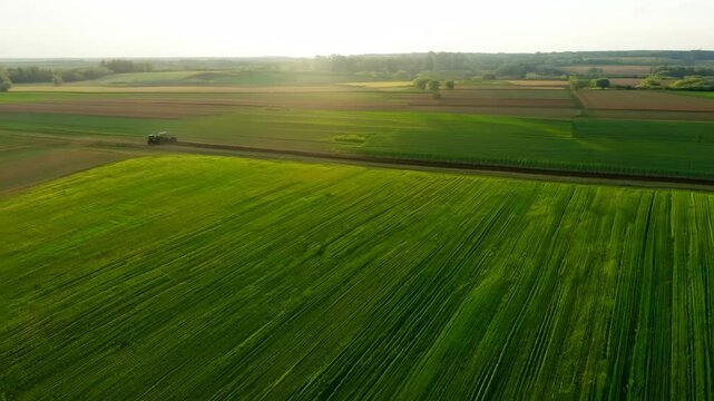 Aerial perspective of agricultural landscape with tractor working on farming fields at daytime